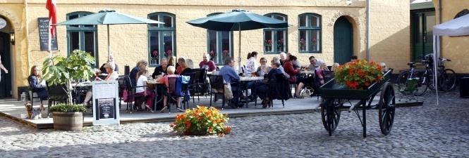 En fyldt terasse på Café CupCake set fra PLUMS GÅRD